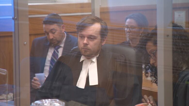 Two lawyers sit behind plexiglass in a courtroom