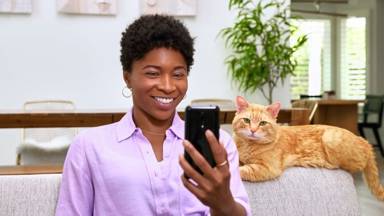 A woman and her cat look at a phone