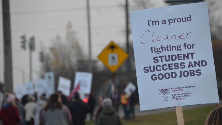 People picketing with signs along a sidewalk.