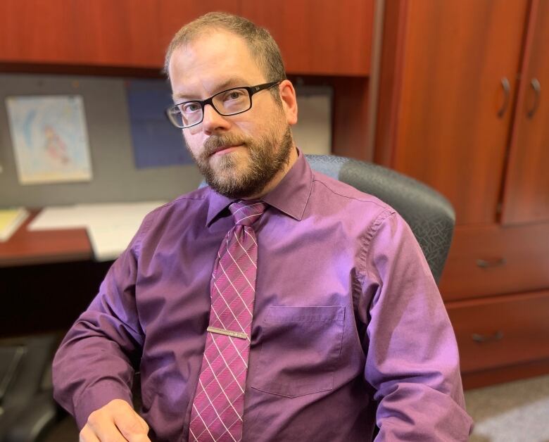 A person in a purple shirt sits at a desk.