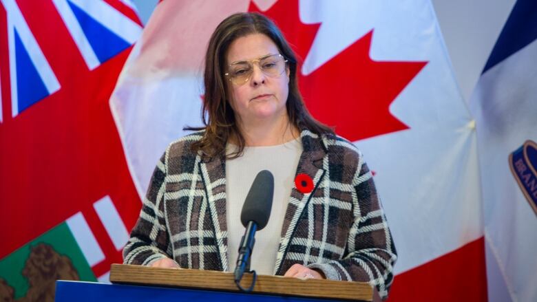 Heather Stefanson stands at a podium, in front of Manitoba and Canada flags.