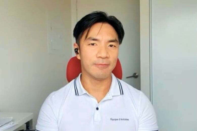 A man wearing a white golf shirt sitting in a red chair