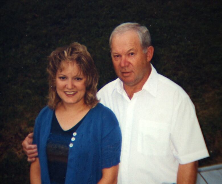 A young woman, left, and a middle-aged man smile into the camera. He has his arm around her.