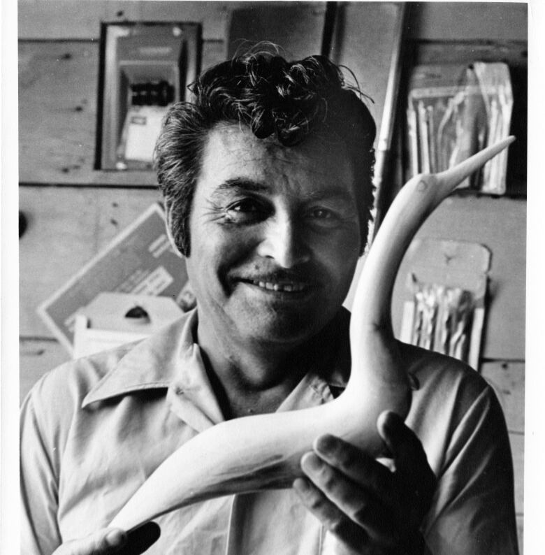 A black and white portrait of a man holding a white carving.