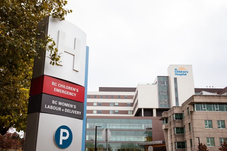 A shot of B.C. Children's Hospital, a large building with multiple departments. A sign out in front reads 'B.C. Children's Emergency' and 'B.C. Women's Labour + Delivery'.