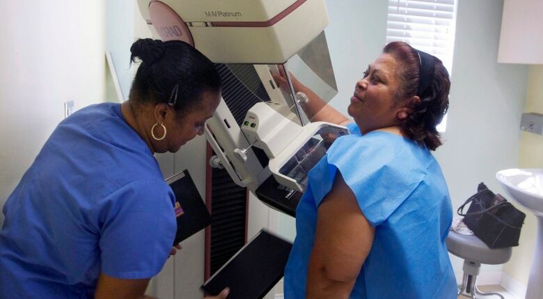 A woman receives a screen-film mammography. 