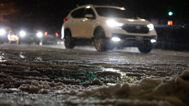 A car is pictured on a road topped with snow.