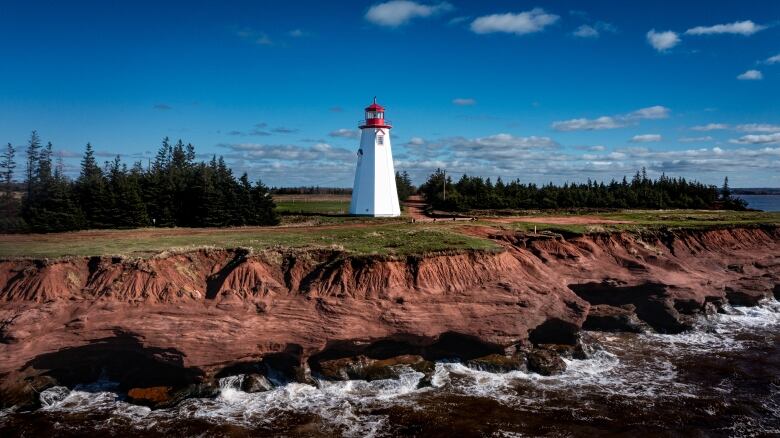 A distance shot of a lighthouse and some cliffs. 