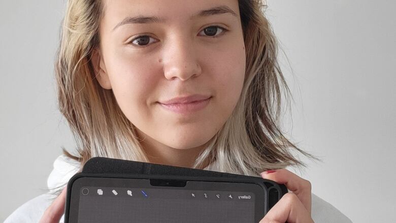 Young girl holding an iPad with a character on the screen.