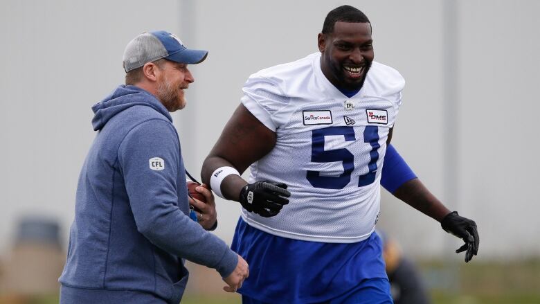 Winnipeg Blue Bombers head coach Mike O'Shea jokes around with Jermarcus Hardrick (51) during practice at training camp in Winnipeg Thursday, May 19, 2022.