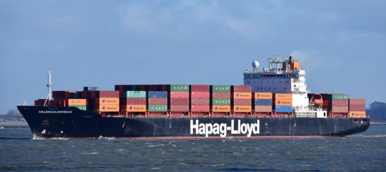 A huge container vessel shown loaded with colourful containers on its deck. 