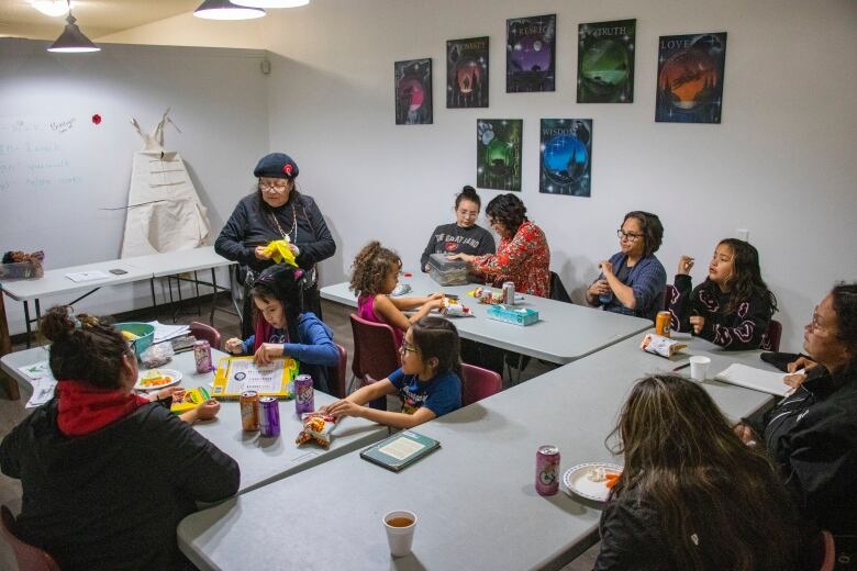 A teacher works with a classroom full of young people to elders.