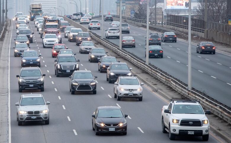 A thick pack of cars travel on an elevated expressway.