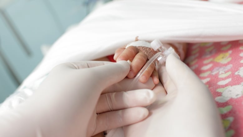 hands in gloves touches and holds hand a little sick child.