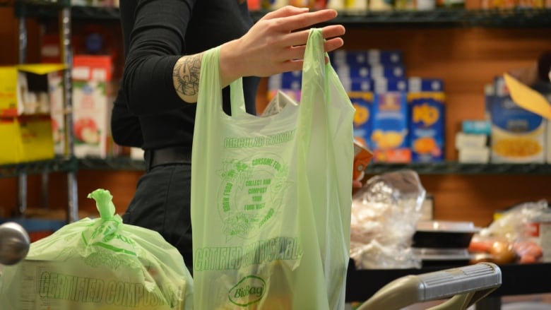 A woman holds a plastic bag filled with cans