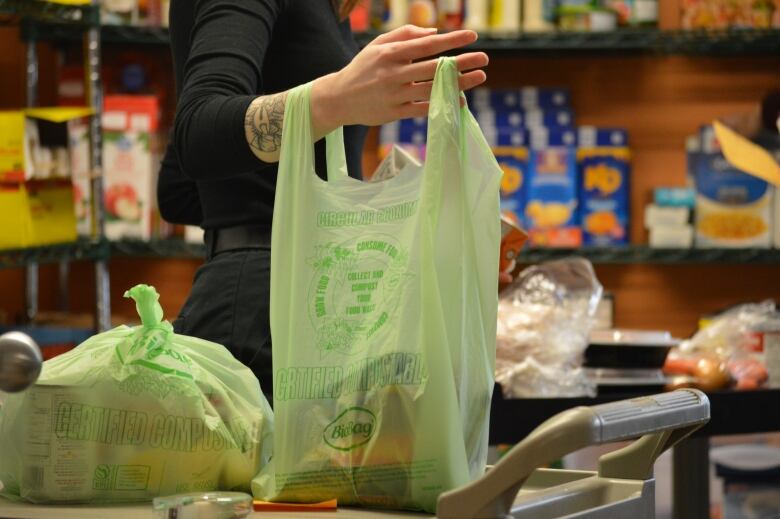 A woman holds a plastic bag filled with cans