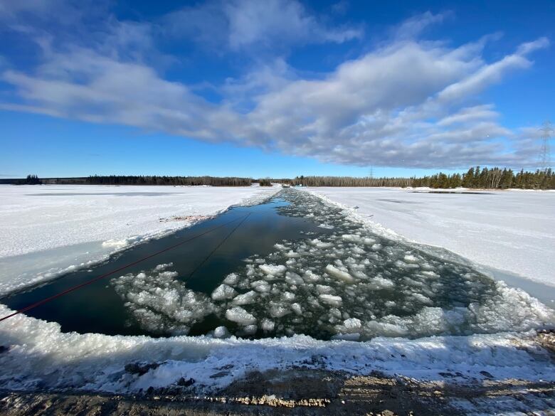 With a thin layer of snow and ice on either side, a narrow path of open water stretches off toward the horizon on the Nelson River.