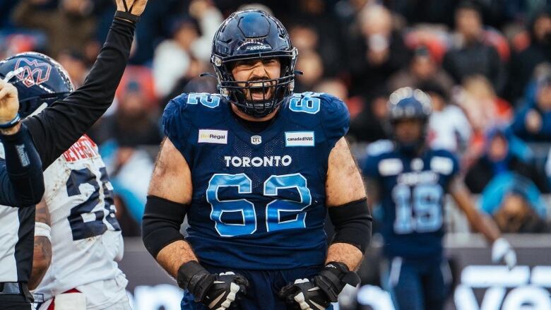 Ryan Hunter roars after a play on the football field wearing his double-blue Toronto Argonauts jersey and helmet. 