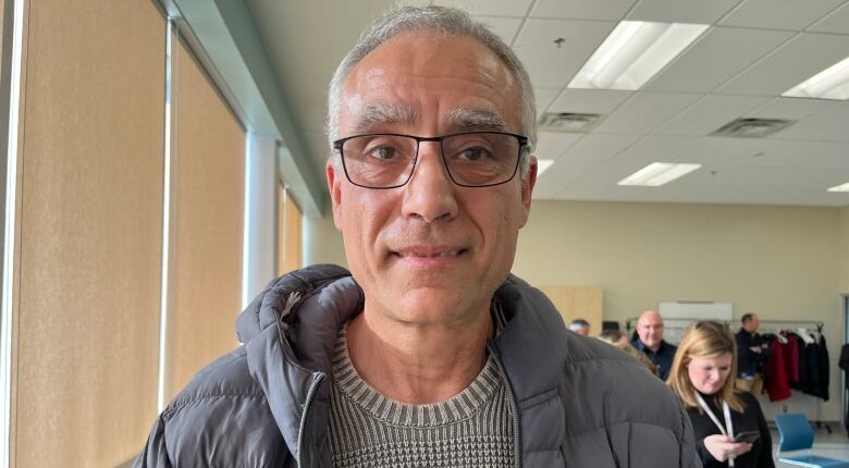 A man with grey hair and glasses smiles into the camera.