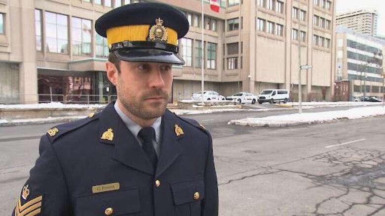 Man in police uniform stands in front of a building. 