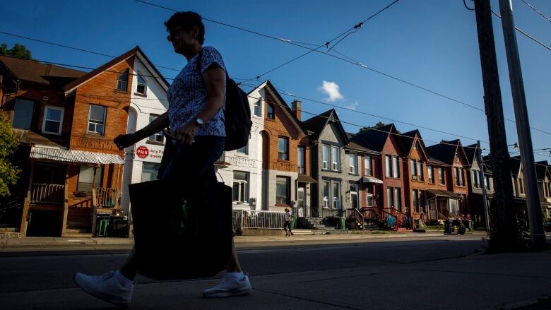 A person walks by a row of houses in Toronto on Tuesday July 12, 2022.The Association of Municipalities of Ontario says provincial housing legislation could leave communities short $5 billion - and taxpayers may have to foot the bill, either in the form of higher property taxes or service cuts.