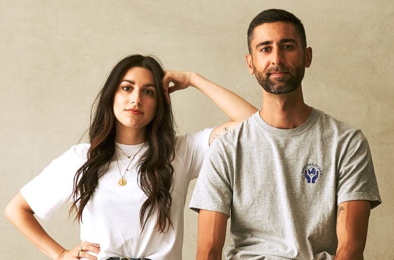 A woman leans on a man's shoulder in a studio portrait. 