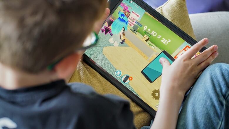 A young boy plays an iPad game with mathematical equations