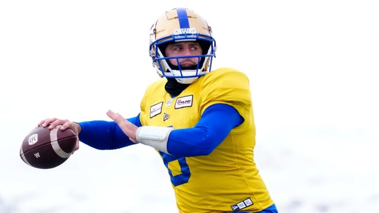 Wearing a yellow practice jersey, Bombers QB Zach Collaros cocks his right arm before throwing the football.