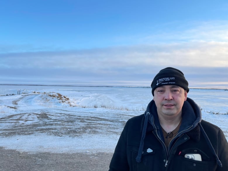 A man in a tuque stands outside.