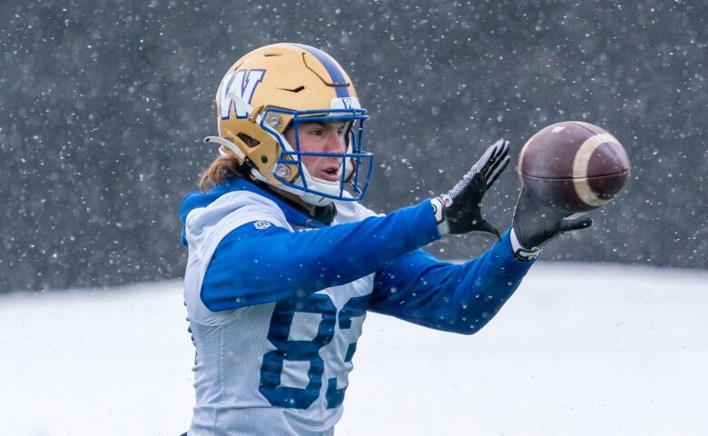 A football player catches the ball in the snow.