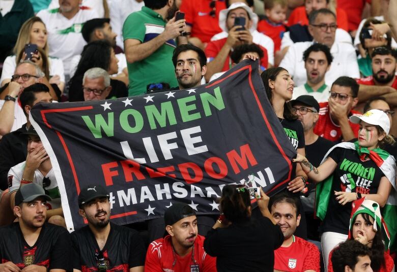 Fans in a stadium holding up a banner.