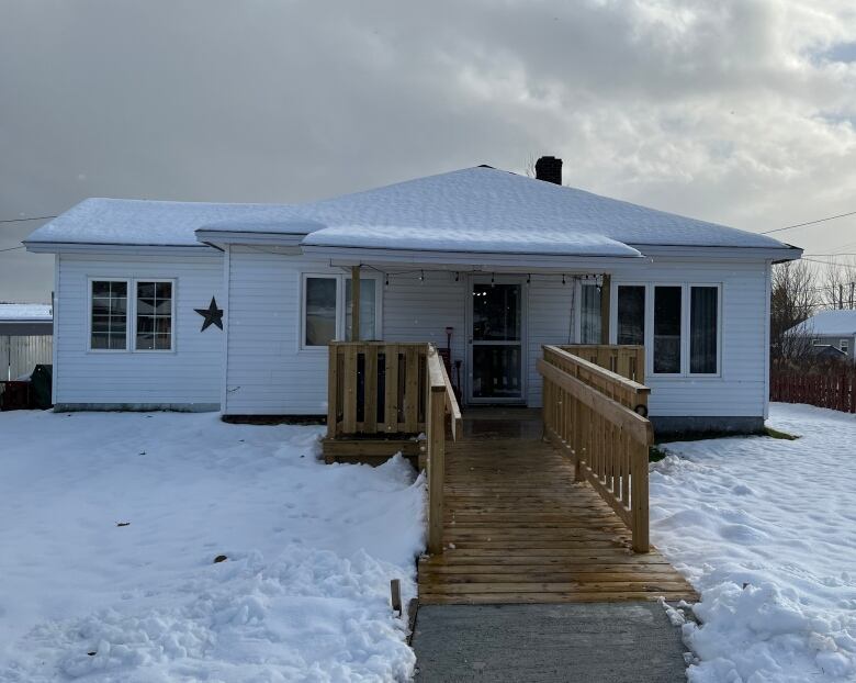 A photo of a one-storey house with a wheelchair-accessible ramp leading straight towards the camera, onto the driveway.