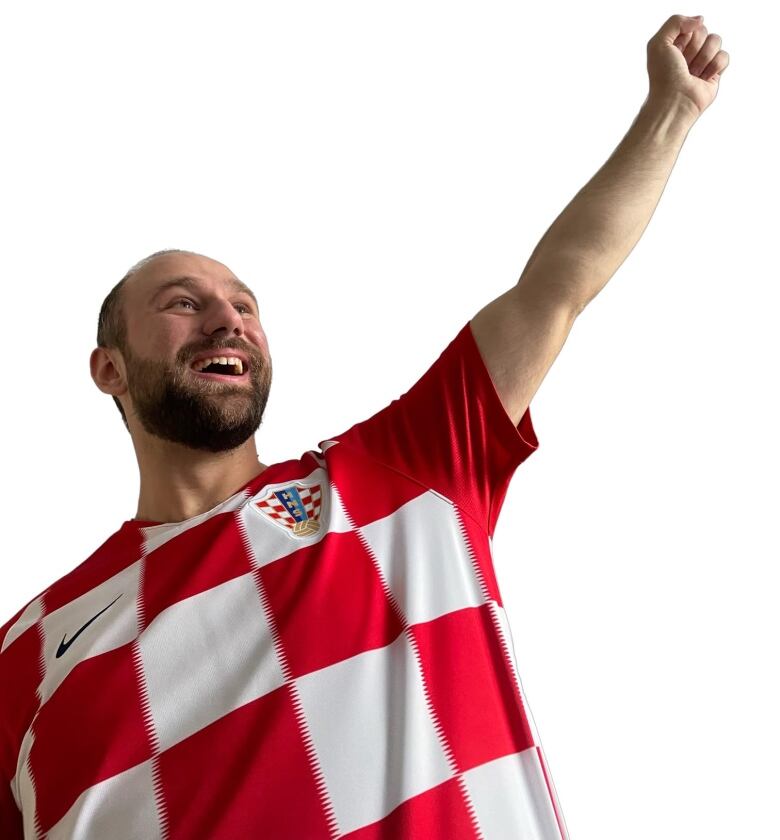 A man in a Croatia jersey holds his fist up triumphantly. 