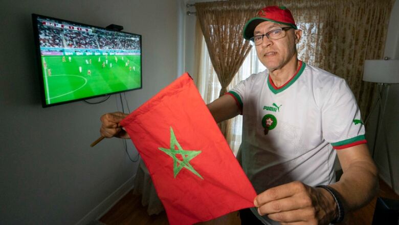 A man holds a Moroccan flag.