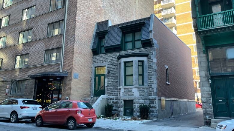 Photos shows an old, two-storey stone house on a downtown residential street.