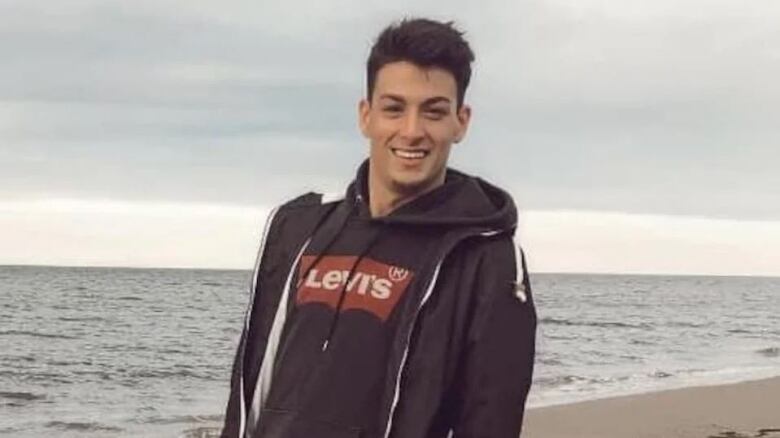 A man standing at a beach, smiling at camera