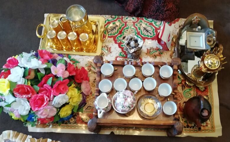 A serving tray of small mugs and colourful flowers. 