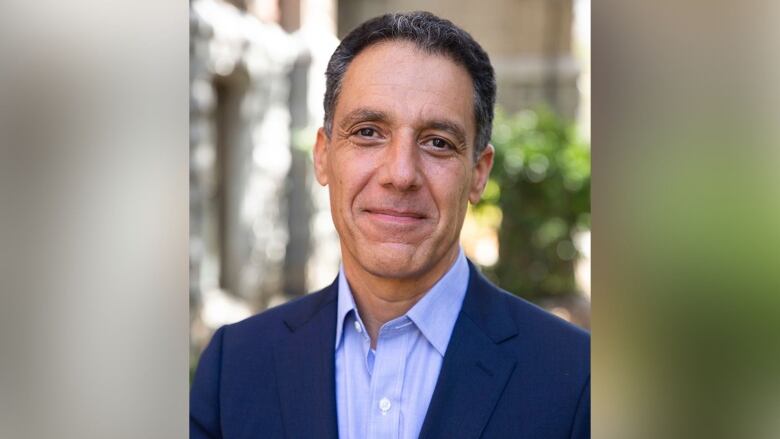 A man in dark suit and blue dress shirt.