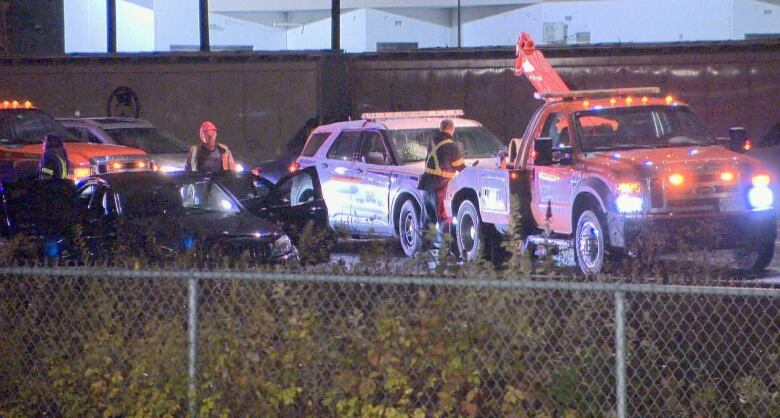 A tow truck and a police vehicle can be seen at one of multiple crime scenes after a robbery and police chase in Coquitlam, B.C., on Nov. 22, 2022.