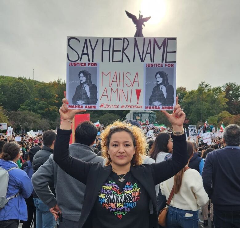 A woman holds a protest sign.