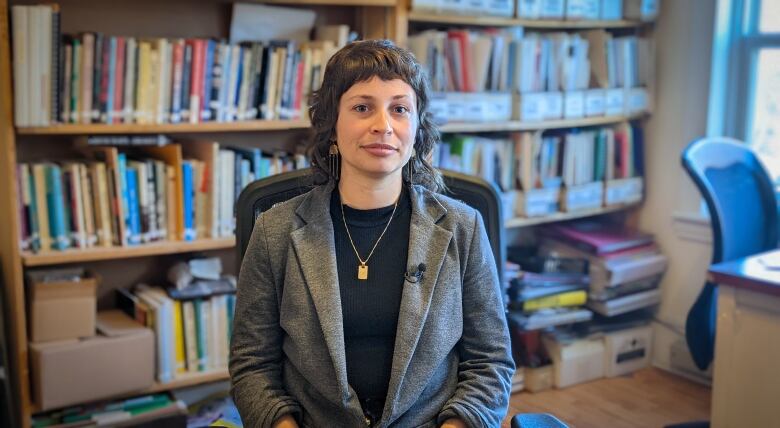 Eliza MacLauchlan seated in front of a wall full of books.