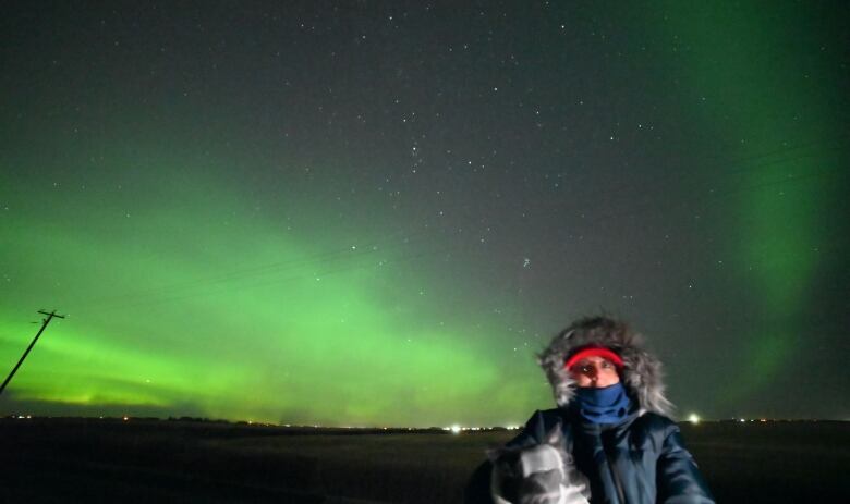 A young boy stands in front of green lights in the night sky