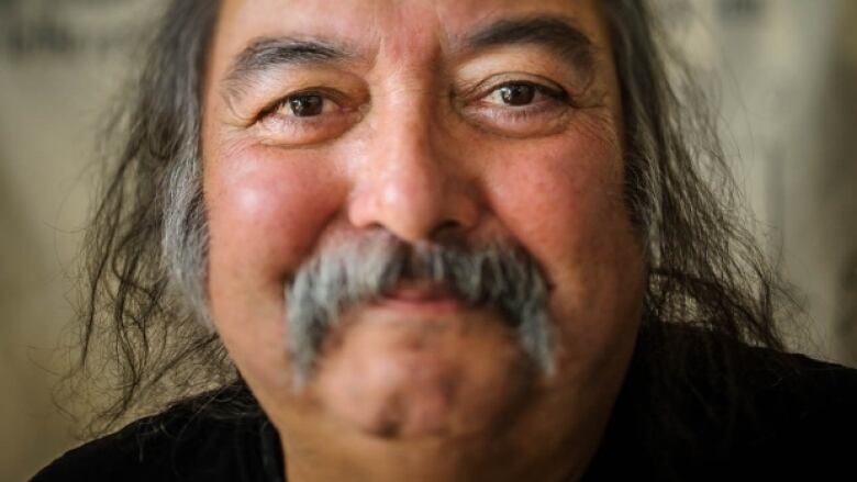 A man smiles at the camera in a closeup image of his face.