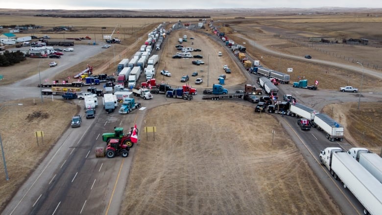 Long lines of semi trucks point in either direction on a divided highway.