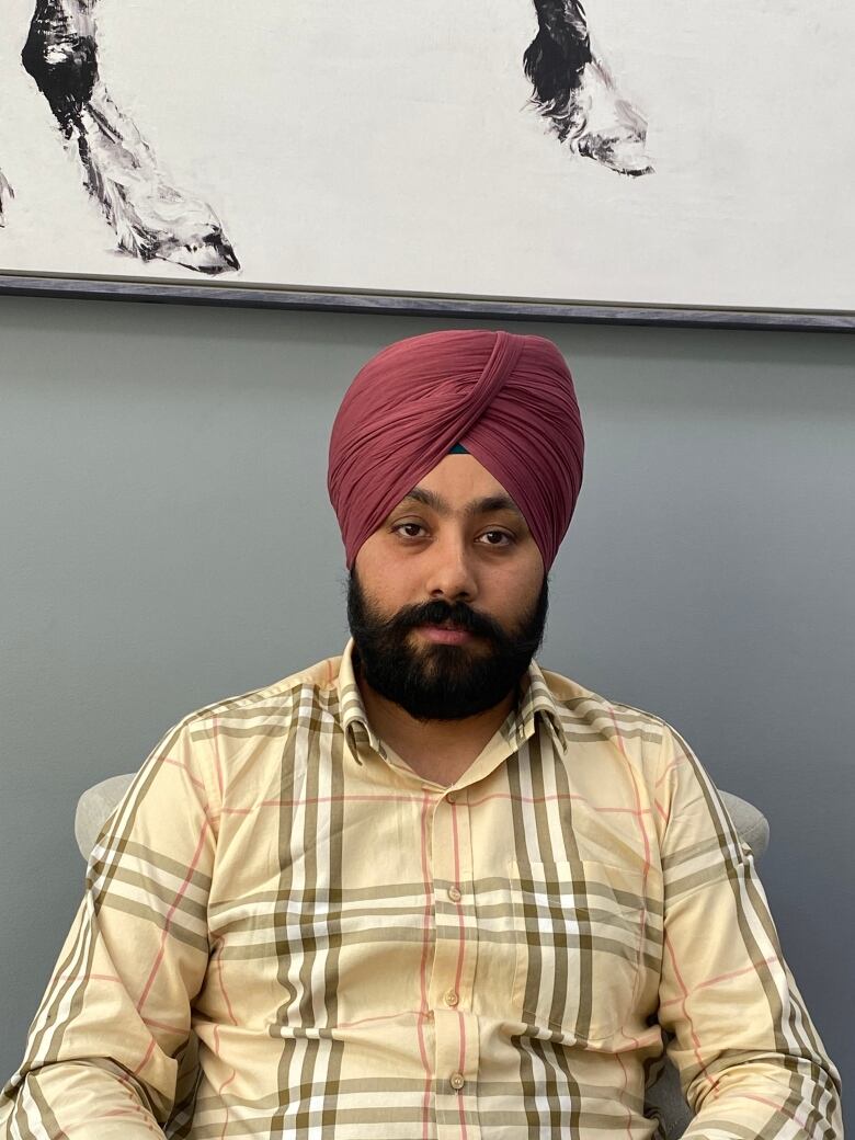 A South Asian man wearing a turban sits in an office chair.