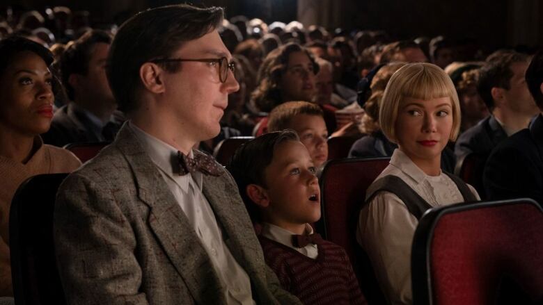 A man, woman and boy watch a movie in a crowded theatre.