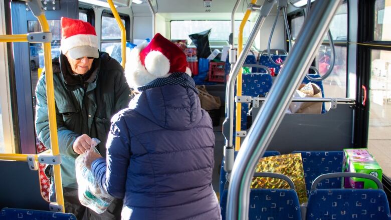 Volunteers carry food donations onto a city bus.