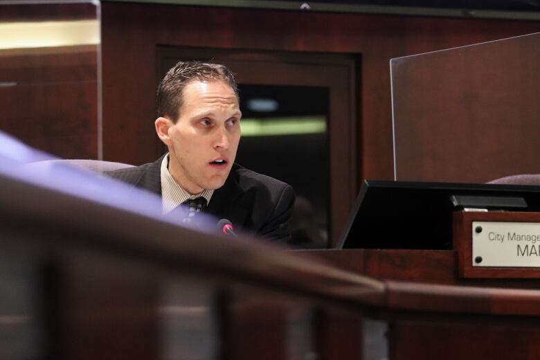 A man speaks into a microphone at a desk.