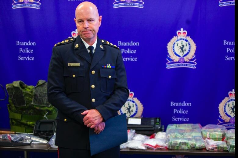 A man in a police uniform stands in front of a table with evidence on it.