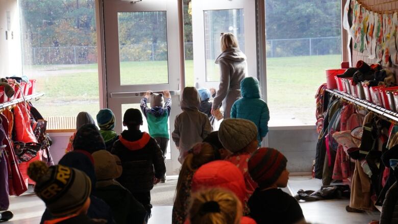 Two rows of kids wearing coats and hats line up to go outside and play at the Echo Bay public school outside of Sault Ste. Marie. 